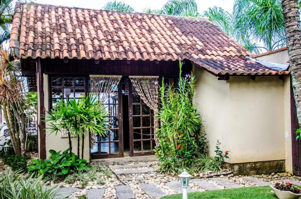 Chalé com telhado colonial cercado de plantas