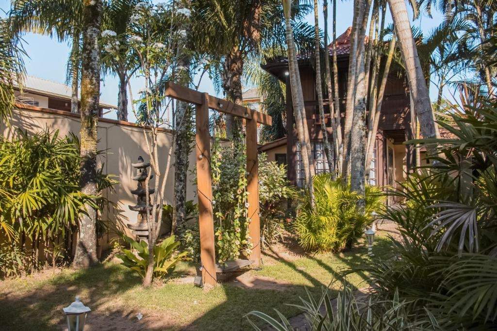 Jardim com pergolado de madeira e palmeiras