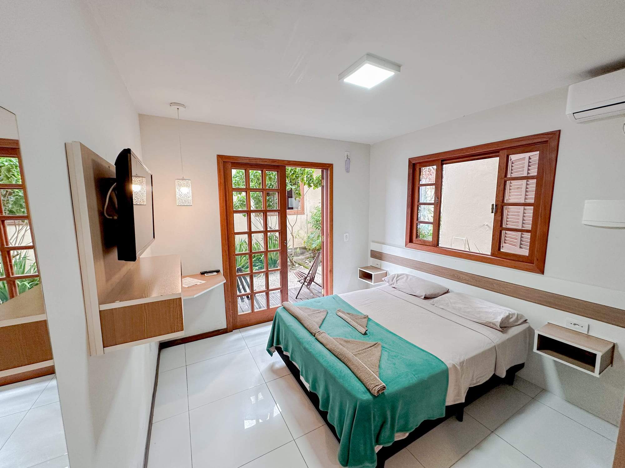 Suíte Térreo com cama de casal, TV e porta para o jardim