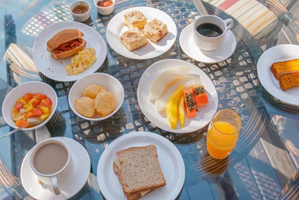 Mesa de café da manhã com frutas, pães, café e suco de laranja