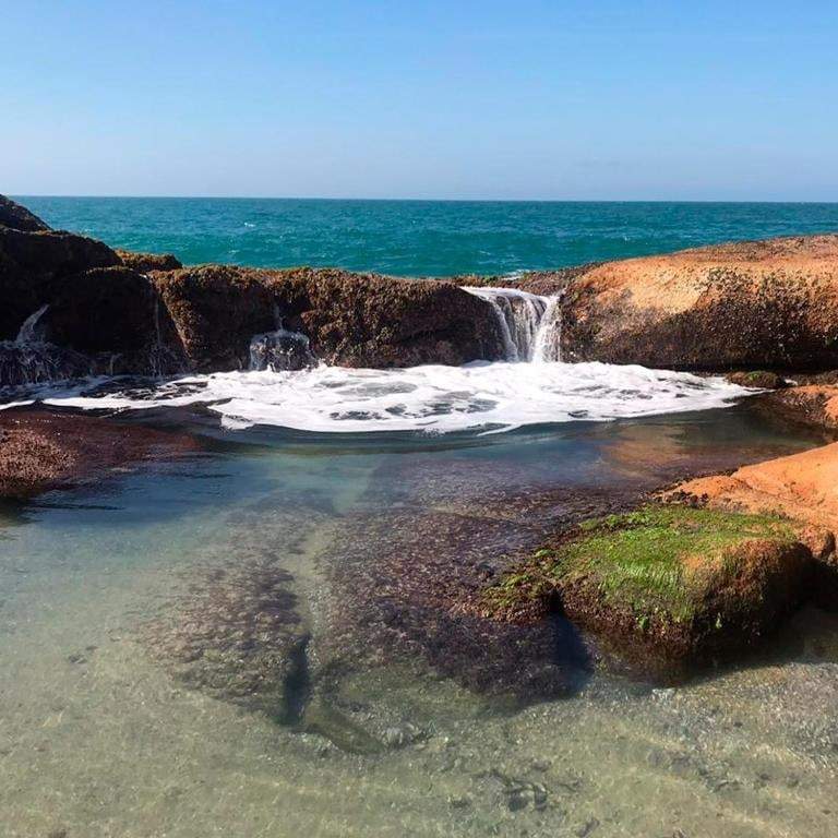 Piscina natural de água cristalina entre as pedras do costão