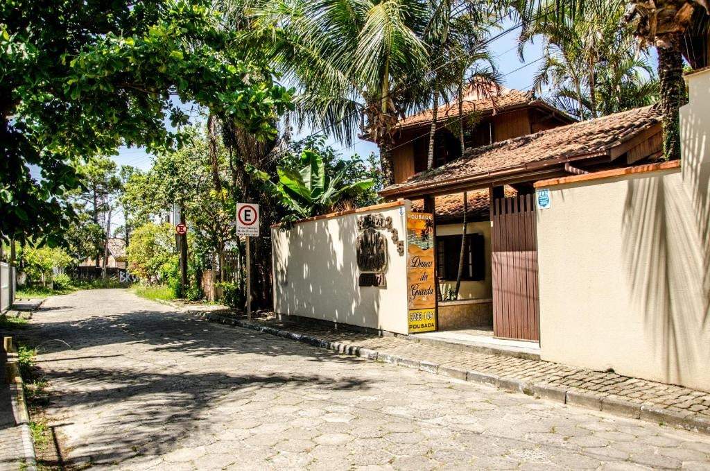 Entrada da pousada numa rua tranquila e arborizada da Guarda do Embaú